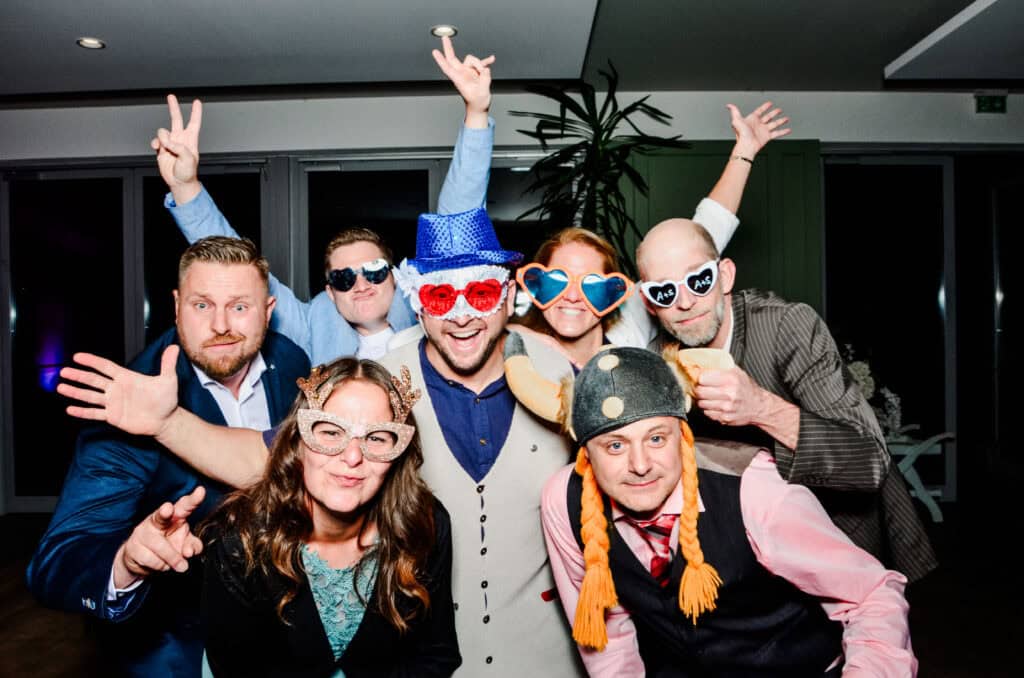Fröhliche Gruppe beim Partyspaß mit bunten Kostümen und verrückten Accessoires. Fotobox Mieten Stadthagen
